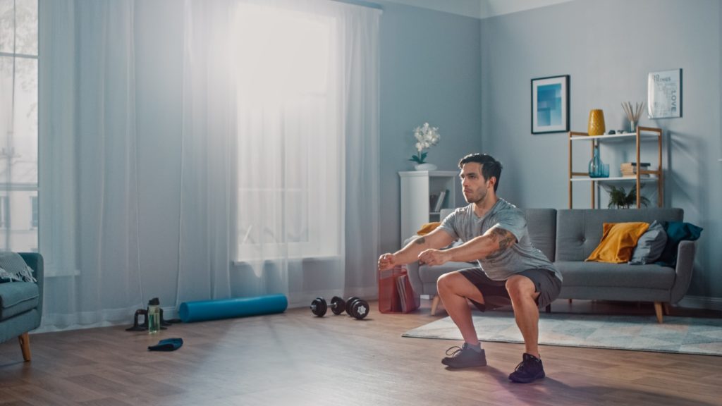 Athletic Fit Man Doing Squat Exercises at Home