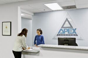 a person checks in with a receptionist at Apex Recovery