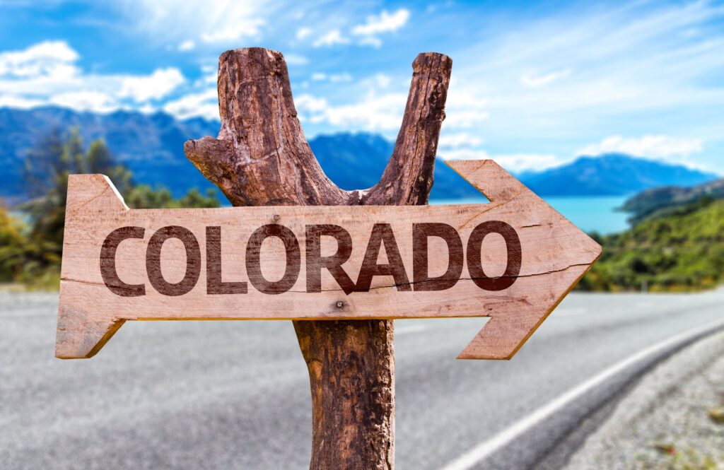 an arrow sign on a lakeside road that says "colorado"