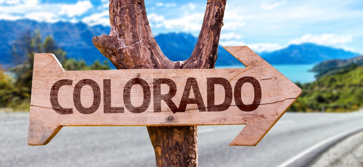 an arrow sign on a lakeside road that says "colorado"