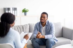 Man sits on couch and talks to therapist about the reasons he went to a drug and alcohol detox center 