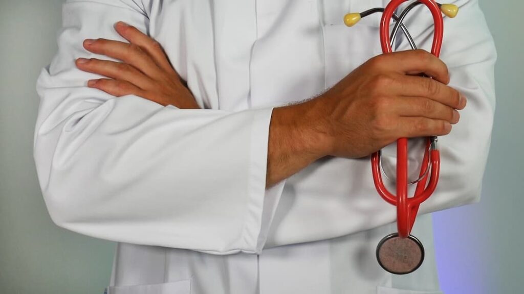 a doctor holds a stethescope with their arms crossed