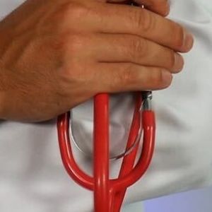 a doctor holds a stethescope with their arms crossed