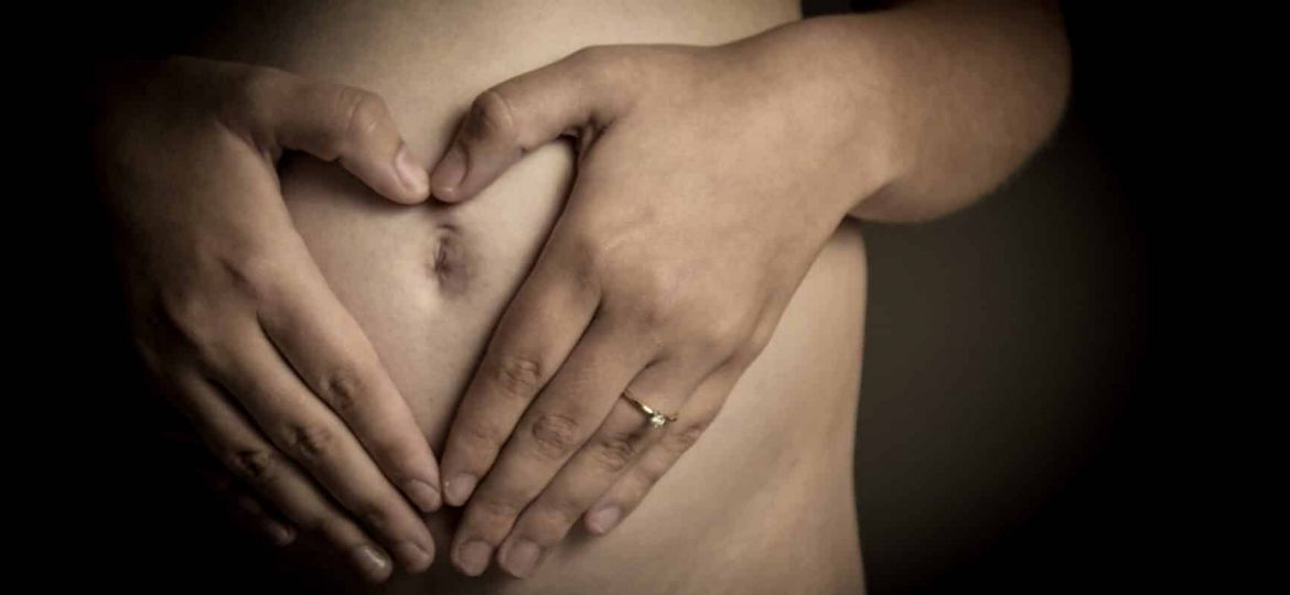 a person holds their stomach in the shape of a heart