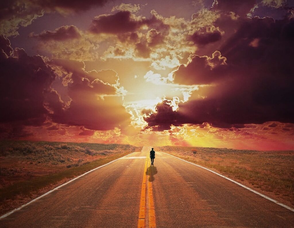 a person walks down the middle of a road at sunset