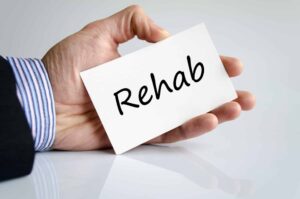 a person holding a card that says "rehab"