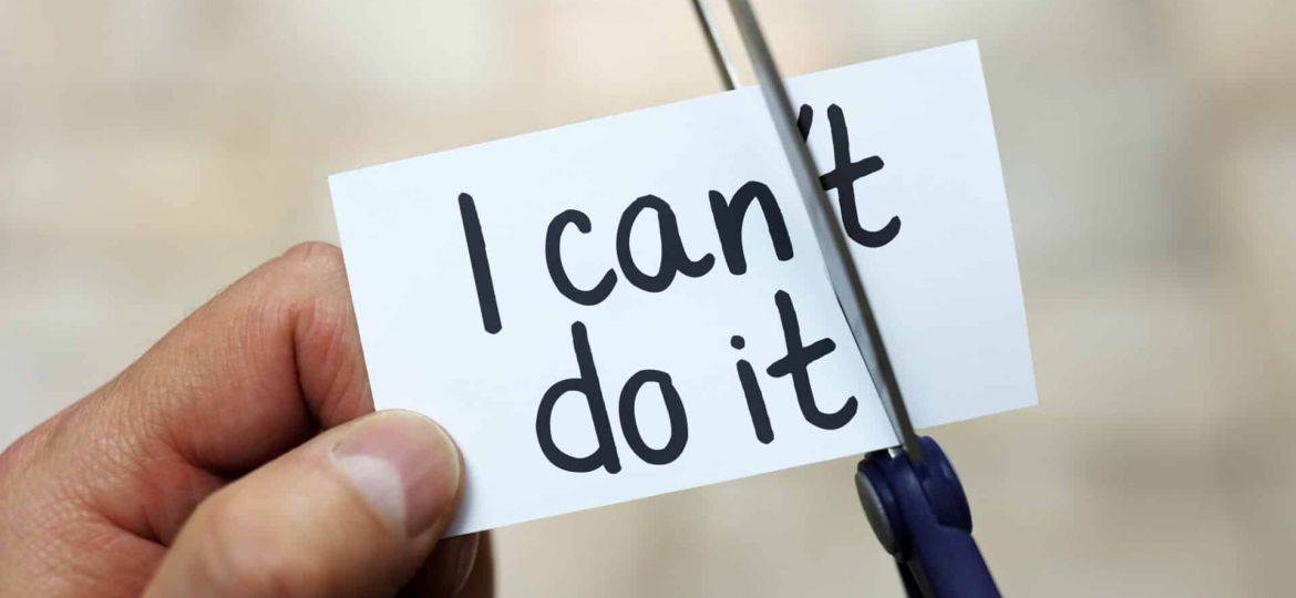 a person cuts the "'t" off of a card reading "I can't do it"