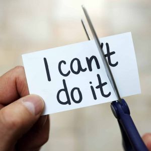 a person cuts the "'t" off of a card reading "I can't do it"