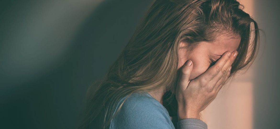 a person holds their face sadly