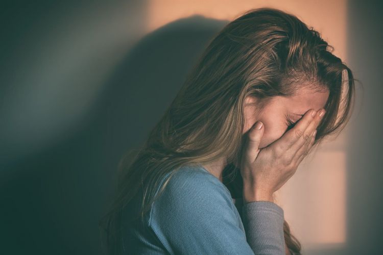 a person holds their face sadly