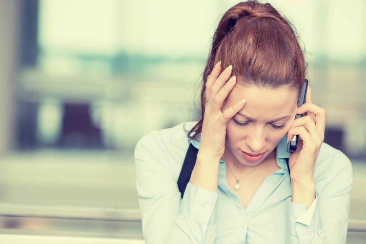 a person holds their head while talking on a phone