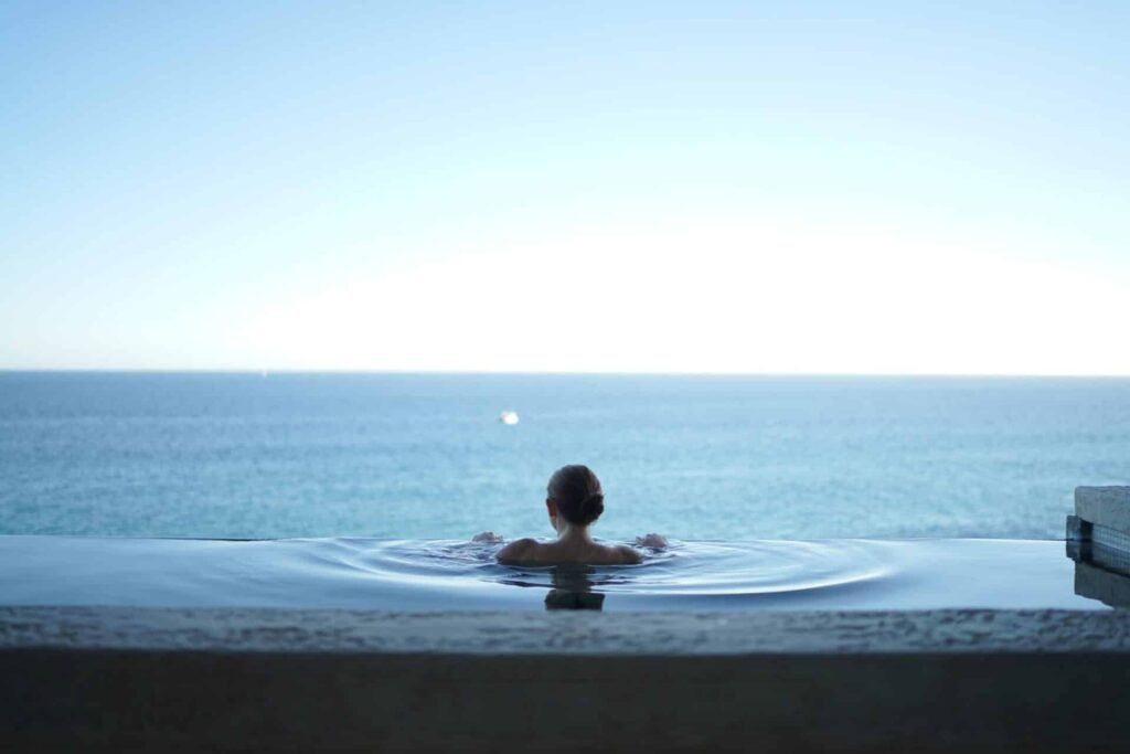 a person looks at the ocean from an infinity pool