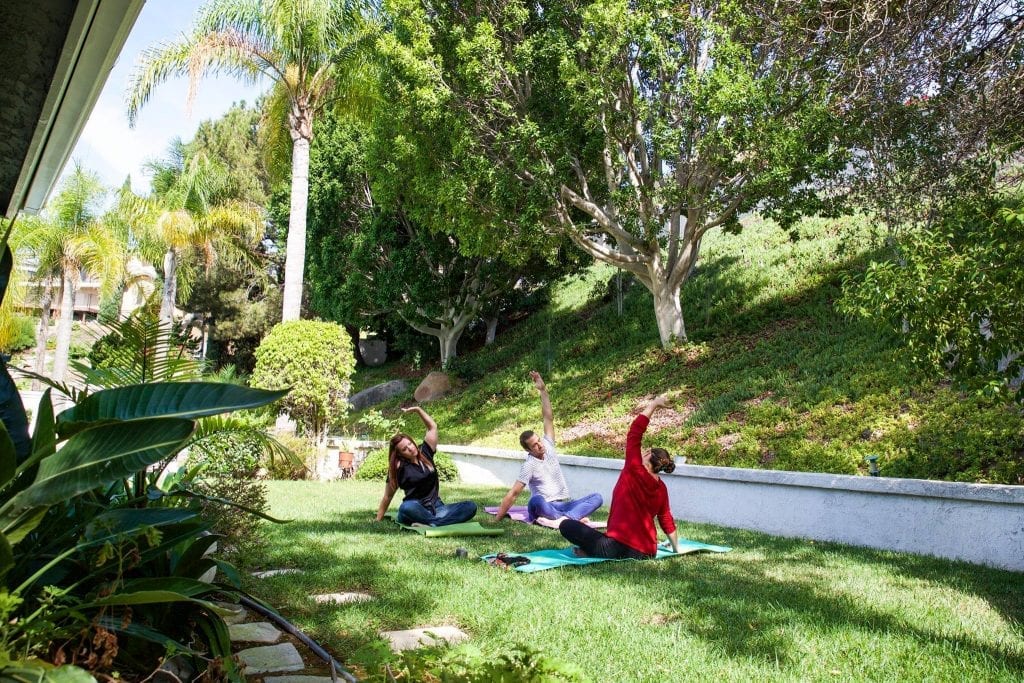people do yoga outside on a green lawn