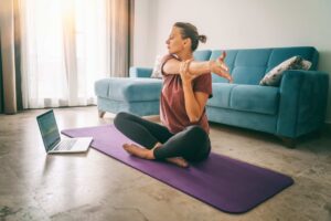 a person follows a computer guide doing yoga at home