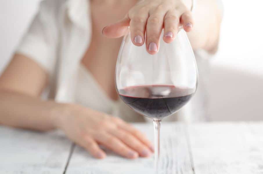 a person holds their hand over a wine glass