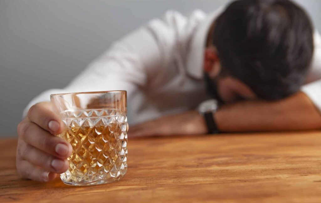 a person passed out holding a glass of alcohol