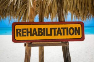 a sign on a beach that reads "rehabilitation"