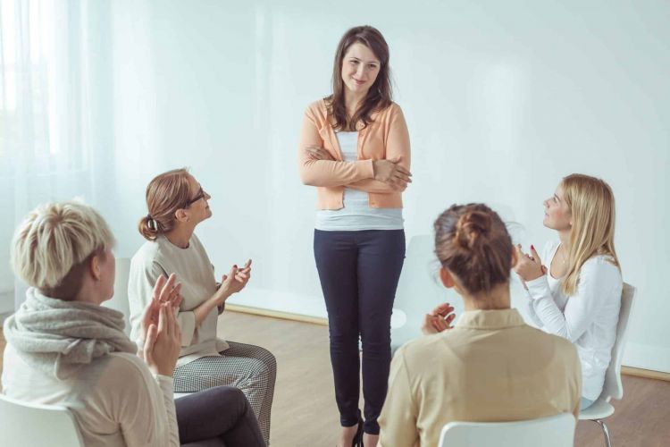 a person stands and shares as a therapy group applauds