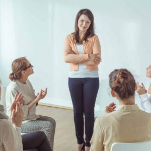 a person stands and shares as a therapy group applauds