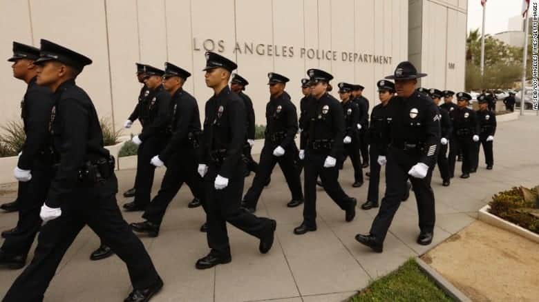 a group of police officers in uniform walk in formation neat the Los Angeles police department