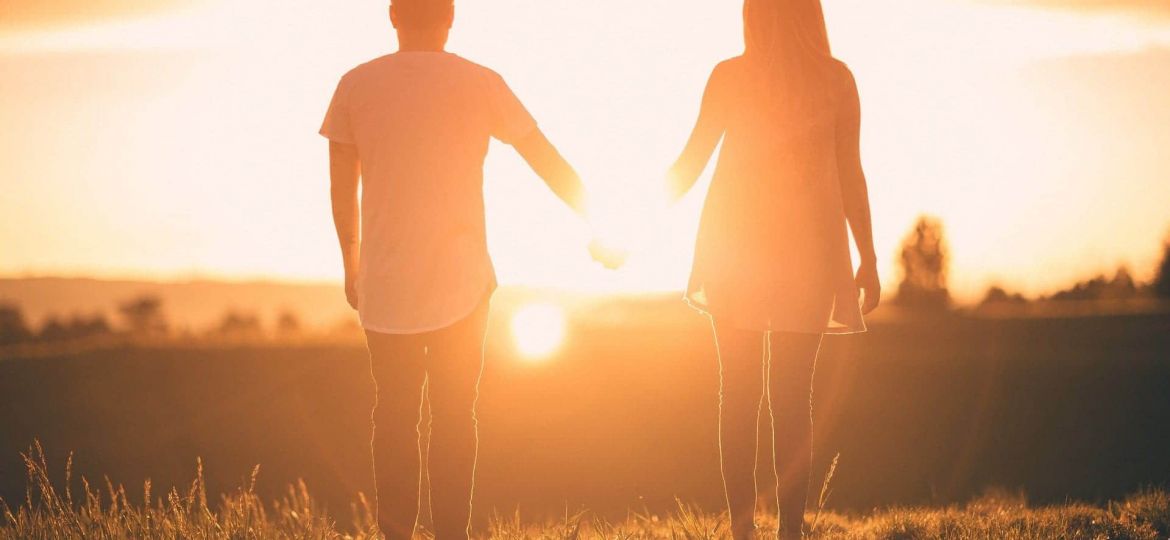 Couple holding hands at sunset.