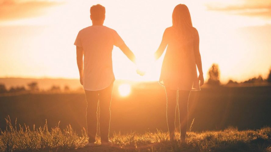 Couple holding hands at sunset.