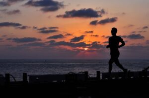 a person runs on an ocean pier at sunset