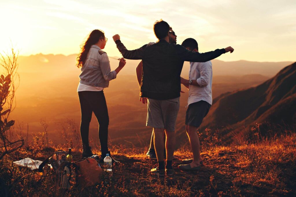 a group celebrates on a mountain ridge at sunset