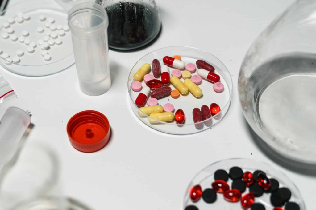 assorted pills in a sample dish near lab equipment