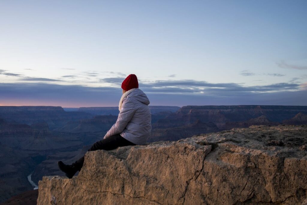 a person sits on the edge of the grand canyon