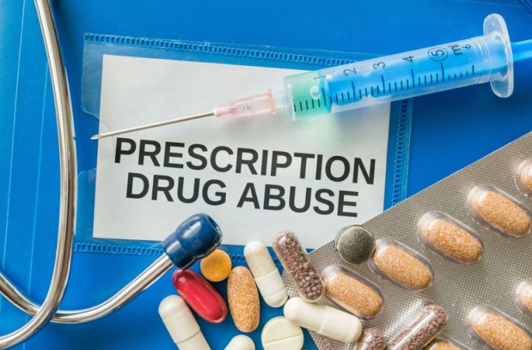 a needle, pills, and a stethoscope on top of a card titled "prescription drug abuse"