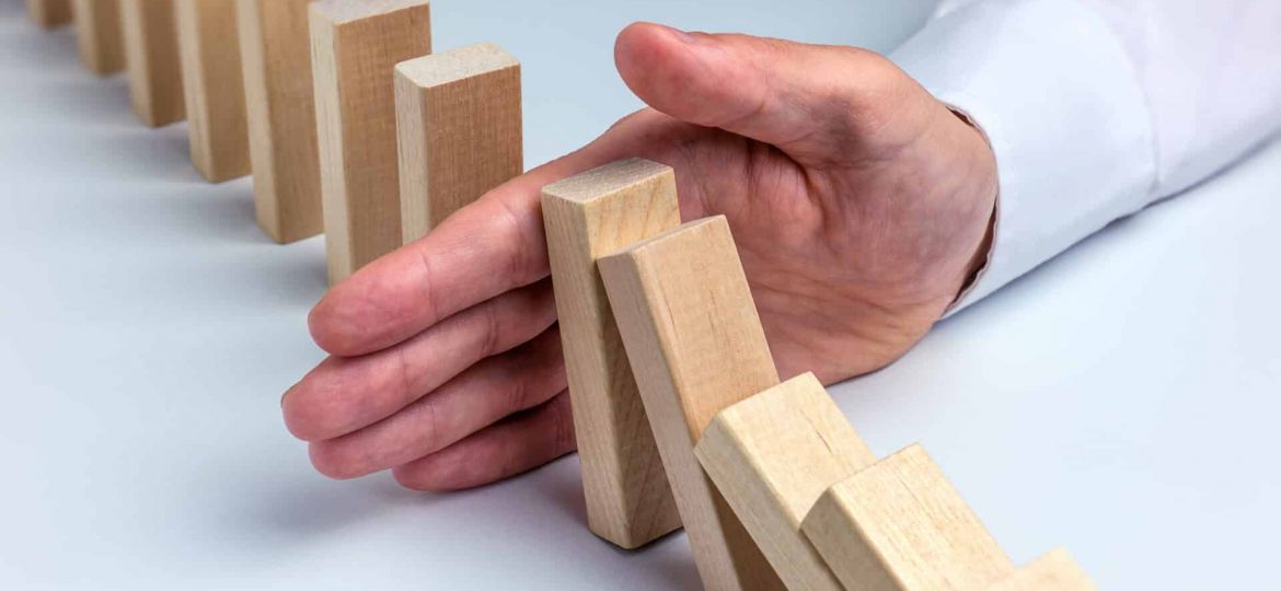a person stops a row of bricks from falling