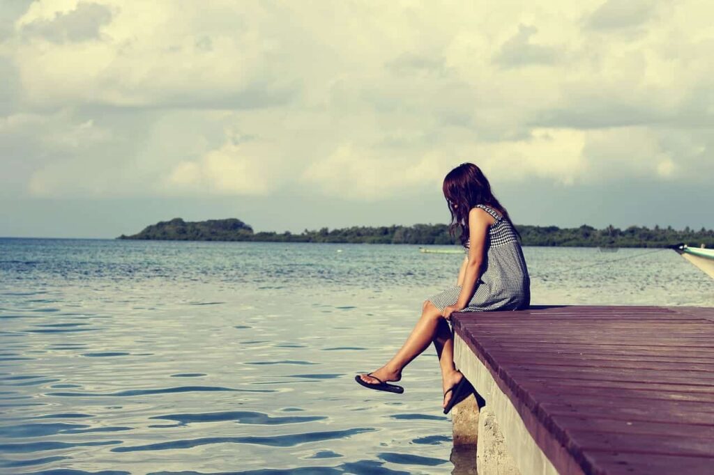 a person sits on a lake pier