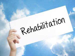 a person holds a card that reads "rehabilitation"