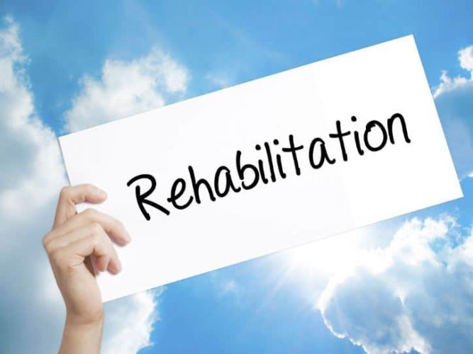 a person holds a card that reads "rehabilitation"