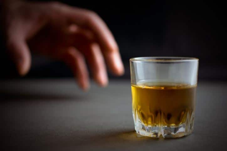 a person reaches for a glass of liquor