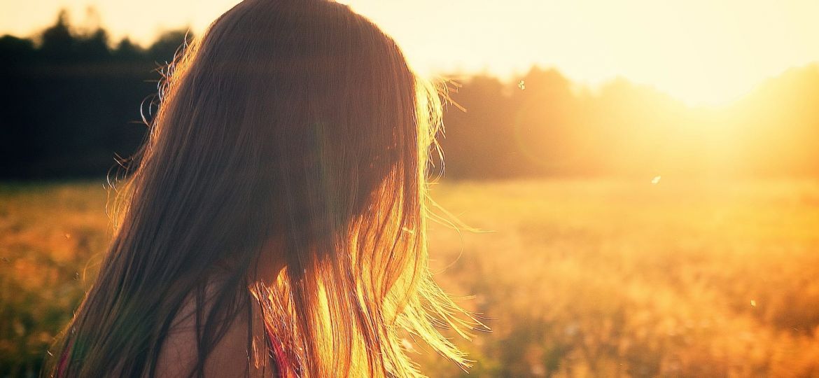 a person walks through a field at sunset