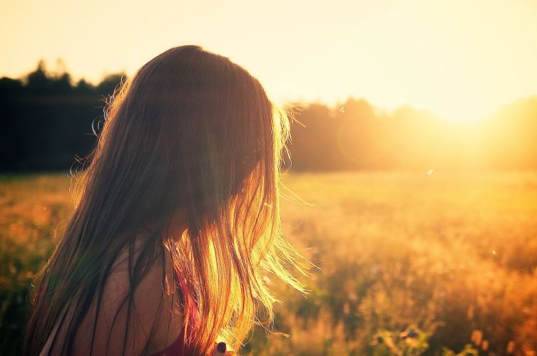 a person walks through a field at sunset