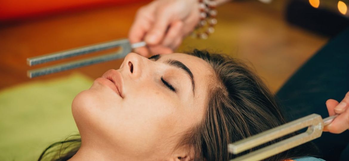 a person lies down awhile someone uses tuning forks near their ears