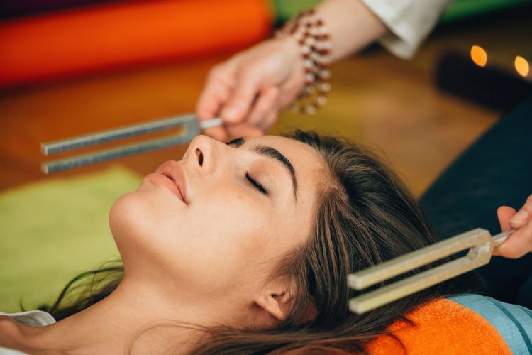 a person lies down awhile someone uses tuning forks near their ears