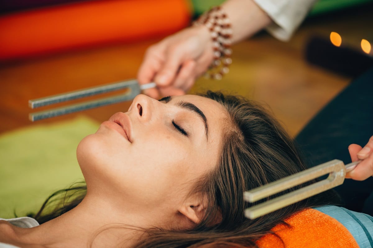 a person lies down awhile someone uses tuning forks near their ears