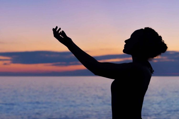 a person does tai chi on a beach at sunset