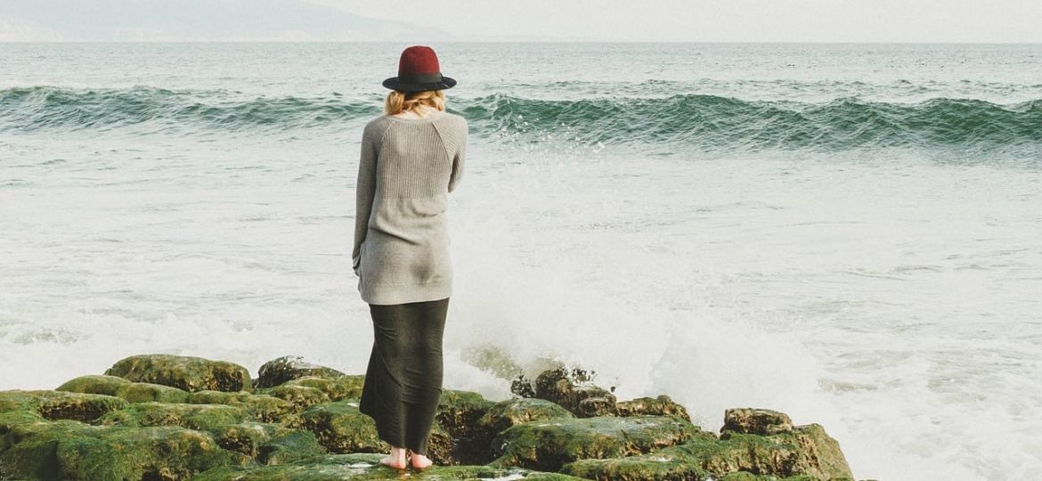 a person stands on a rock looking at the ocean