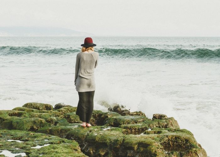 a person stands on a rock looking at the ocean