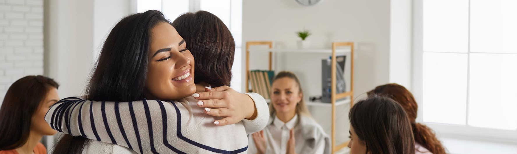 two women hug in a therapy support group