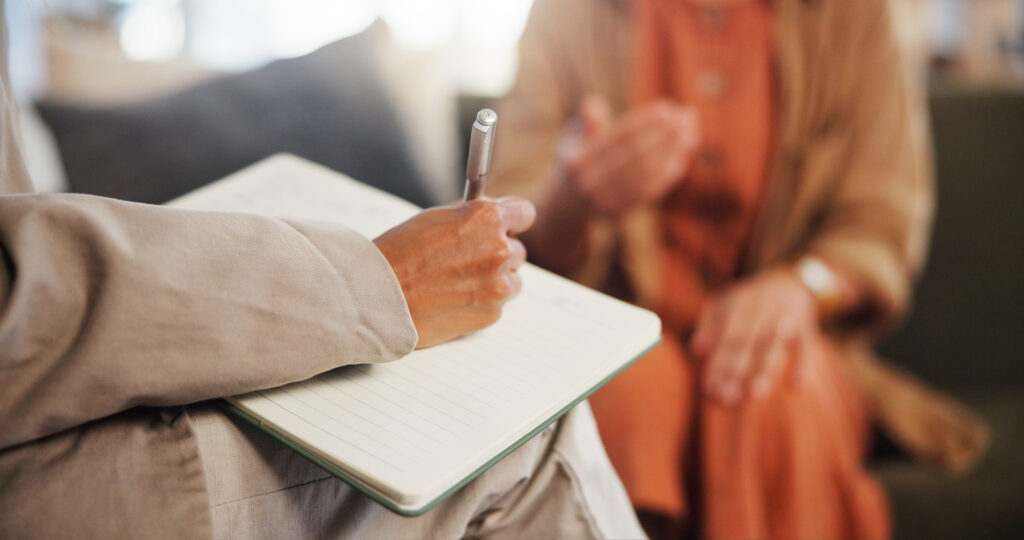 Therapist is taking notes on a notepad during a therapy session for bipolar disorder