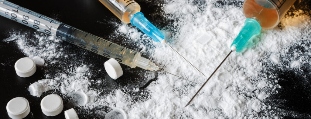 Illicit substances and syringes on a black table