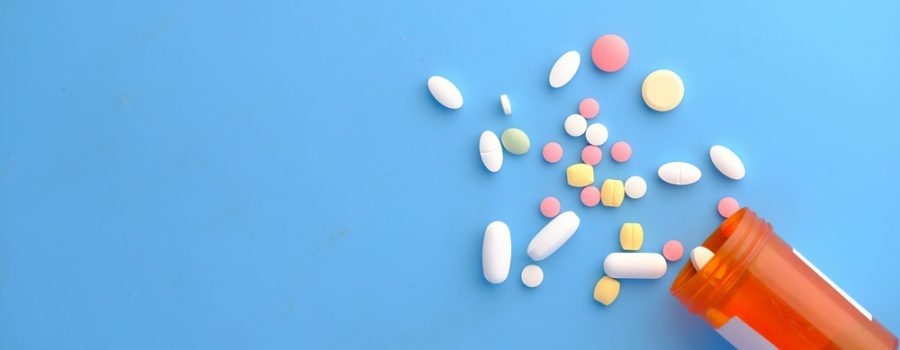 Pills spilled on a blue background from a prescription pill bottle