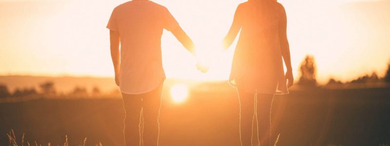 Couple holding hands at sunset.