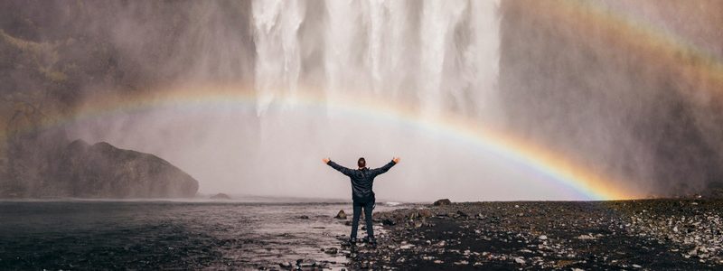 man stands underneath rainbow free from addiction